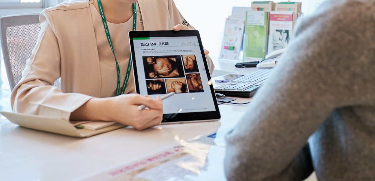 A doctor explaining ultrasound images to a patient on a tablet